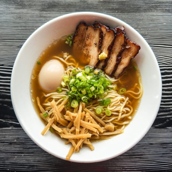 A bowl of Susukino Ramen with noodles, broth, sliced pork, a boiled egg, bamboo shoots, and green onions.