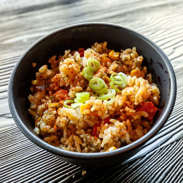 A close-up of a bowl of Susukino Ramen Bar's fried rice, garnished with green onions.